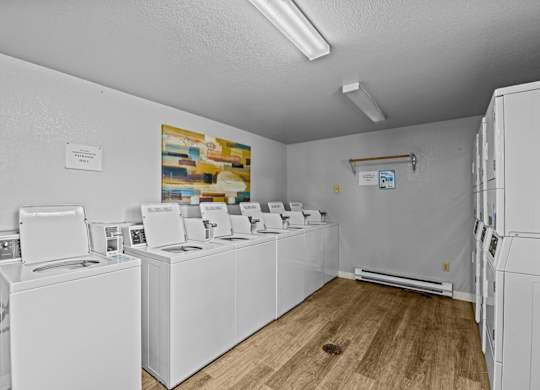 A laundry room with a row of washers and dryers.