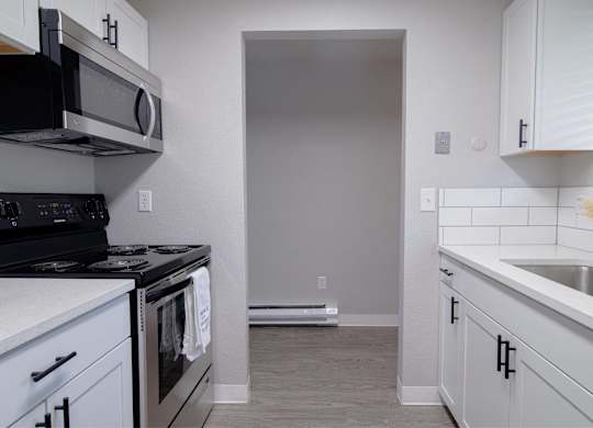 A kitchen with white cabinets and a black stove top oven.