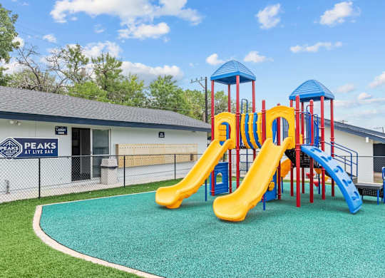 Colorful playground with slides and safety surfacing at Peaks at Live Oak Apartments, Texas, 78233