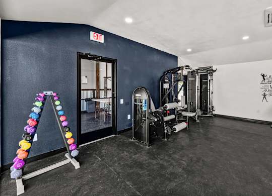 Fitness center with dumbbells and strength training machines at Peaks at Live Oak Apartments, Texas