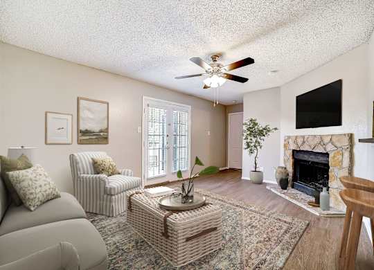 Living room with ceiling fan and stone fireplace at Peaks at Universal City Apartments, Texas, 78148