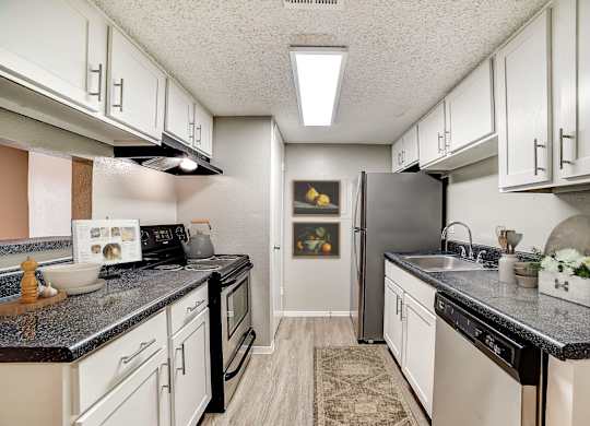 Galley kitchen with white cabinets and stainless steel appliances at Peaks at Universal City Apartments, Texas, 78148