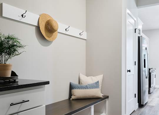 A kitchen with a bench and a hat hanging on a hook.