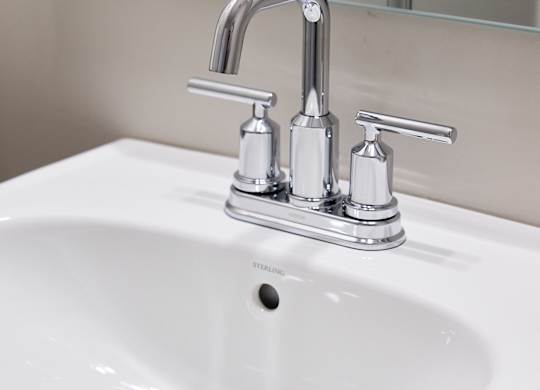 A white sink with a chrome faucet and a mirror above it.