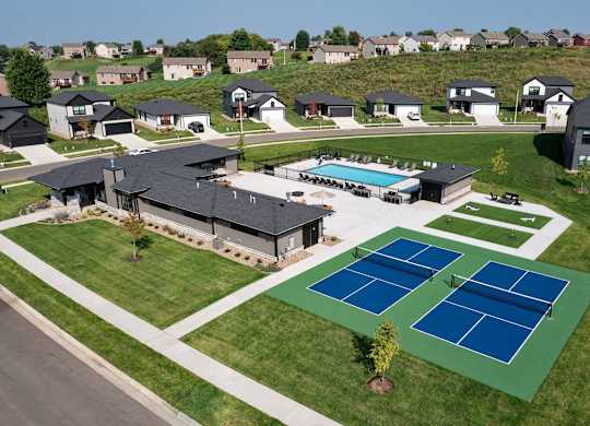 A tennis court is located in the foreground of a residential area.