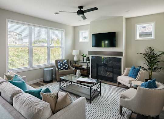 A living room with a fireplace, a television, and a ceiling fan.