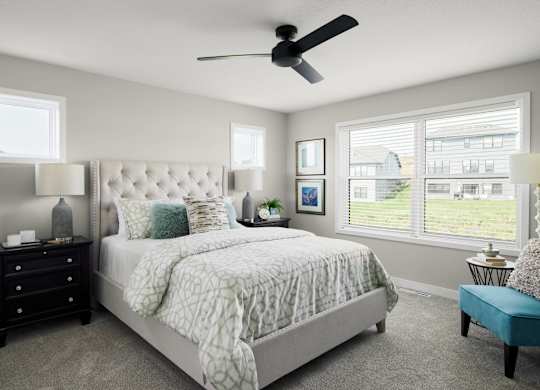 A bedroom with a large bed, a ceiling fan, and a window with blinds.