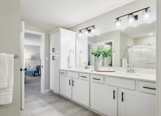 A white bathroom with a mirror and lights above it.