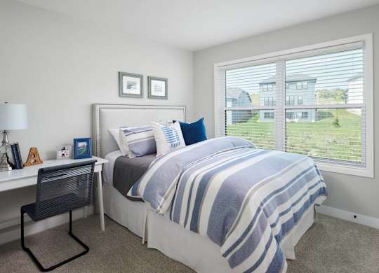 A bedroom with a bed, desk, and chair.