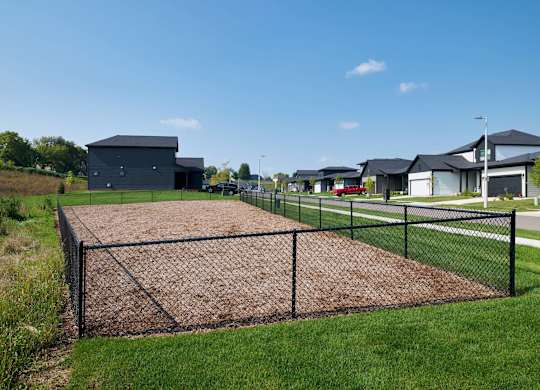A dog park with a chain link fence and a building in the background.