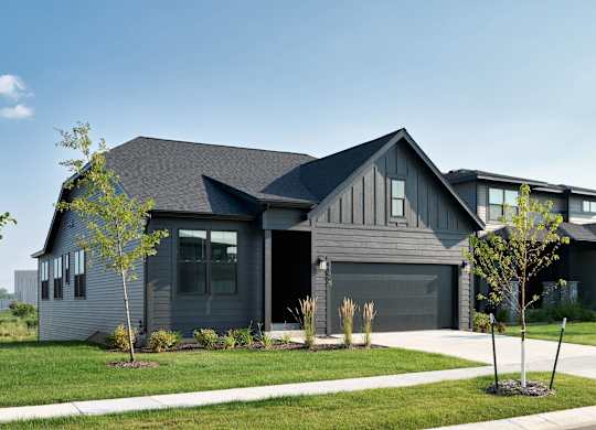 A modern house with a grey exterior and a black garage door.