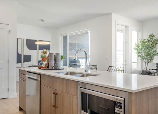 A modern kitchen with a white countertop and stainless steel appliances.