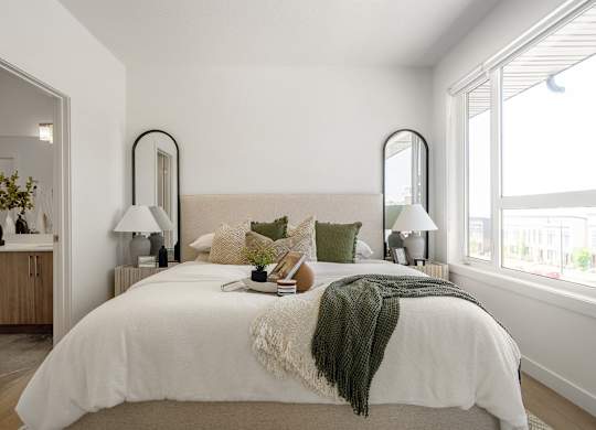 A bedroom with a large bed and two lamps.