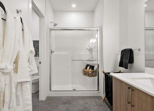 A bathroom with a white shower stall and a white sink.