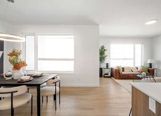 A modern dining room with a table set for two and a couch in the background.