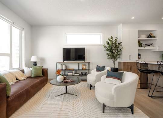 A living room with a brown couch, a white chair, and a coffee table.