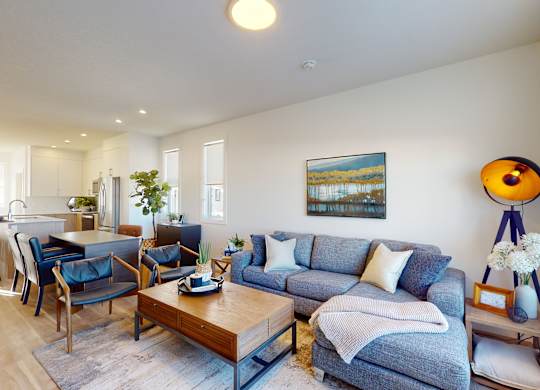 A living room with a blue couch and a painting on the wall.