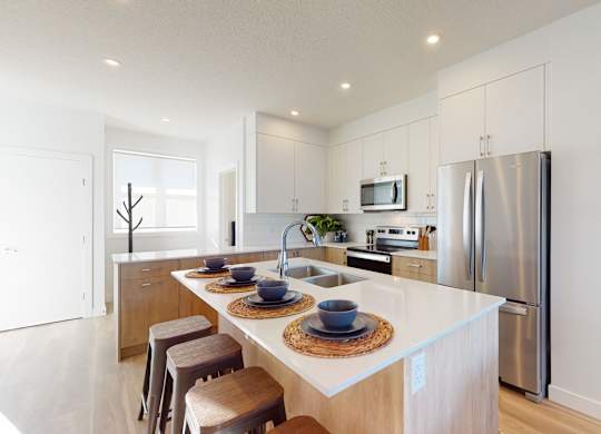 A modern kitchen with a white countertop and stainless steel appliances.