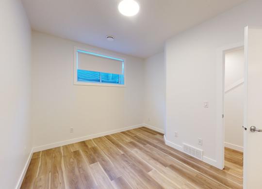 A room with a white door and a window with a blue sky reflection.