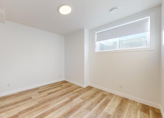 A room with wooden flooring and a window with blinds.