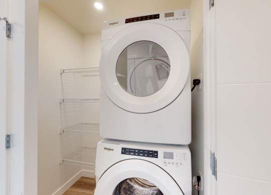 A white dryer is stacked on top of a white washing machine.