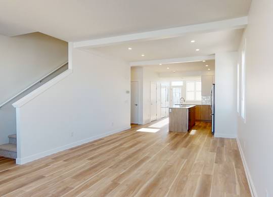 A spacious room with wooden flooring and white walls.