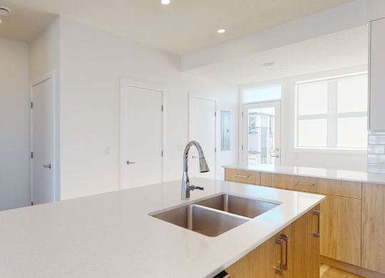 A modern kitchen with a white countertop and a stainless steel sink.