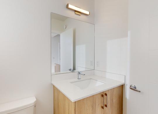 A white bathroom with a sink, toilet, and mirror.