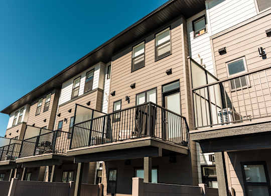 A row of townhouses with balconies and black railings.