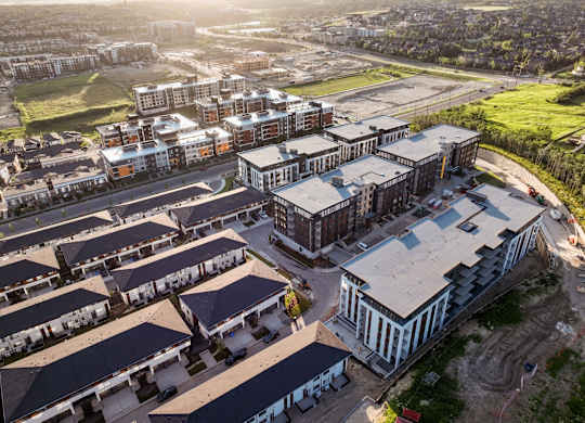 A large building complex with a mix of modern and traditional architecture is surrounded by smaller buildings and greenery.