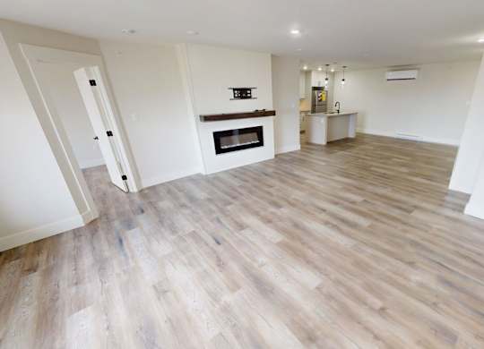A spacious room with wooden flooring and a fireplace.