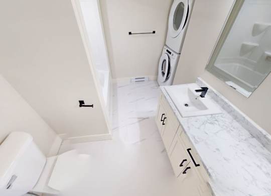 A white bathroom with a washer and dryer built into the cabinetry.