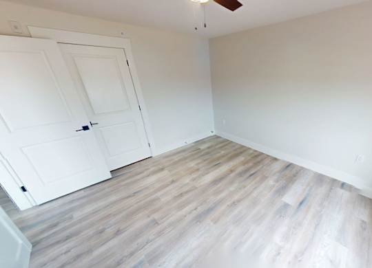 A room with a white door and wooden flooring.