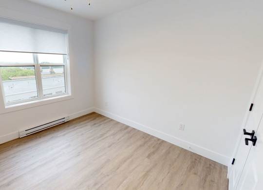 A room with a window and wooden flooring.