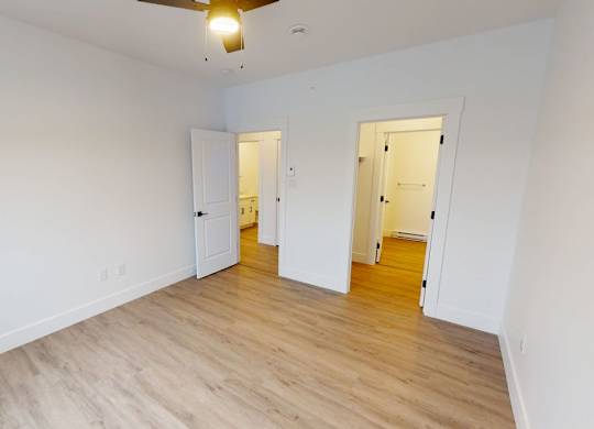 A room with a ceiling fan and two doors.
