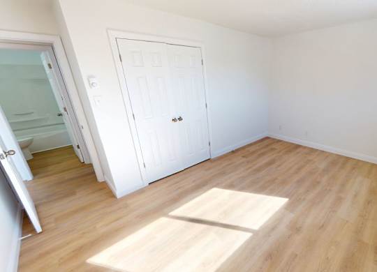 A room with a white door and wooden flooring.