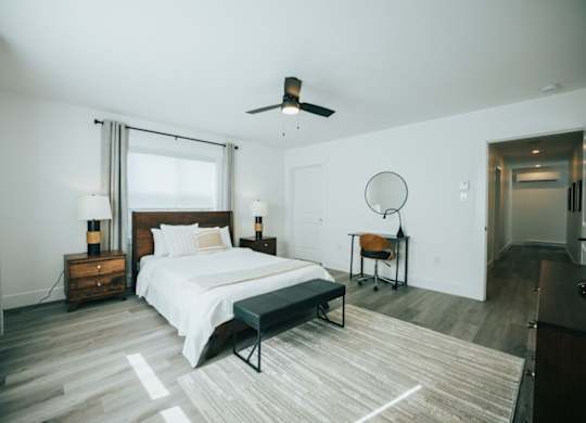 A bedroom with a bed, a chair, and a ceiling fan.