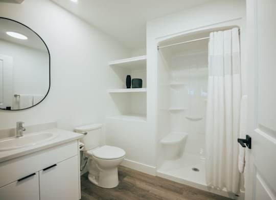 A white bathroom with a toilet, sink, and shower.