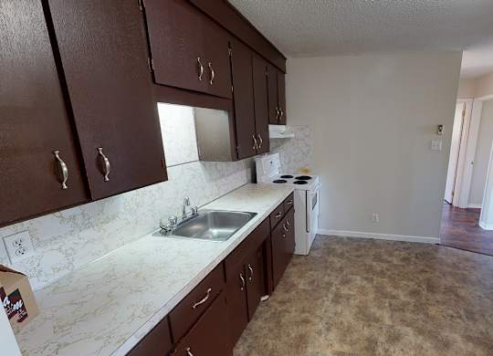 A kitchen with brown cabinets and a white sink.