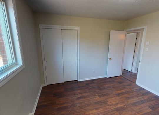 A room with a window and a wooden floor.