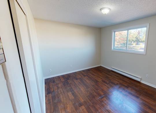 A room with a window and wooden flooring.