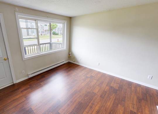 A room with a wooden floor and two windows.