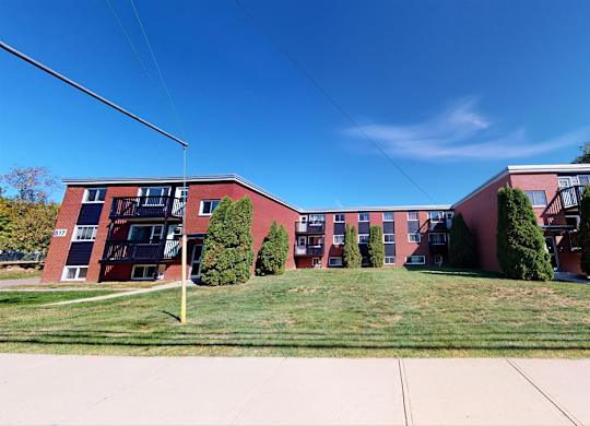 A red brick building with a green lawn in front.
