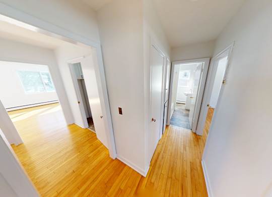 A long hallway with white walls and wood floors.