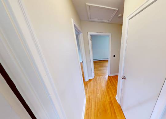 A long hallway with a wooden floor and white walls.