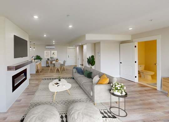 A modern living room with a grey sofa, a coffee table, and a TV mounted on the wall.