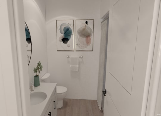 A white bathroom with a toilet, sink, and two wall hangings.