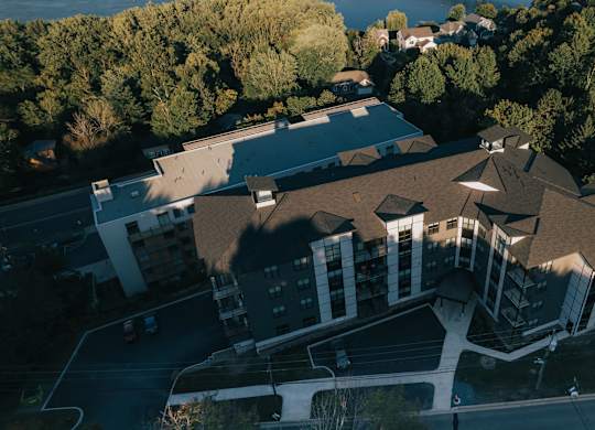 A large building with a brown roof is surrounded by trees.