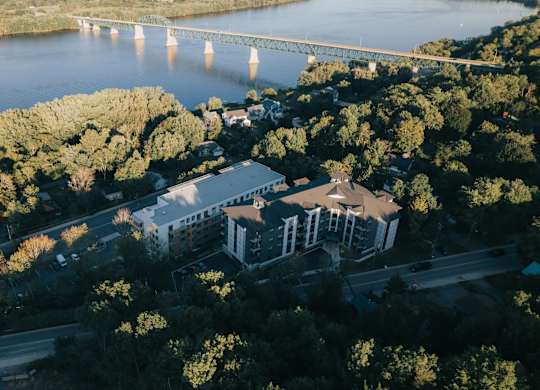 A bridge spans a river in a city with a large building in the foreground.