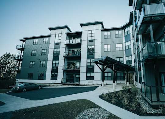 A modern apartment building with a car parked in front.
